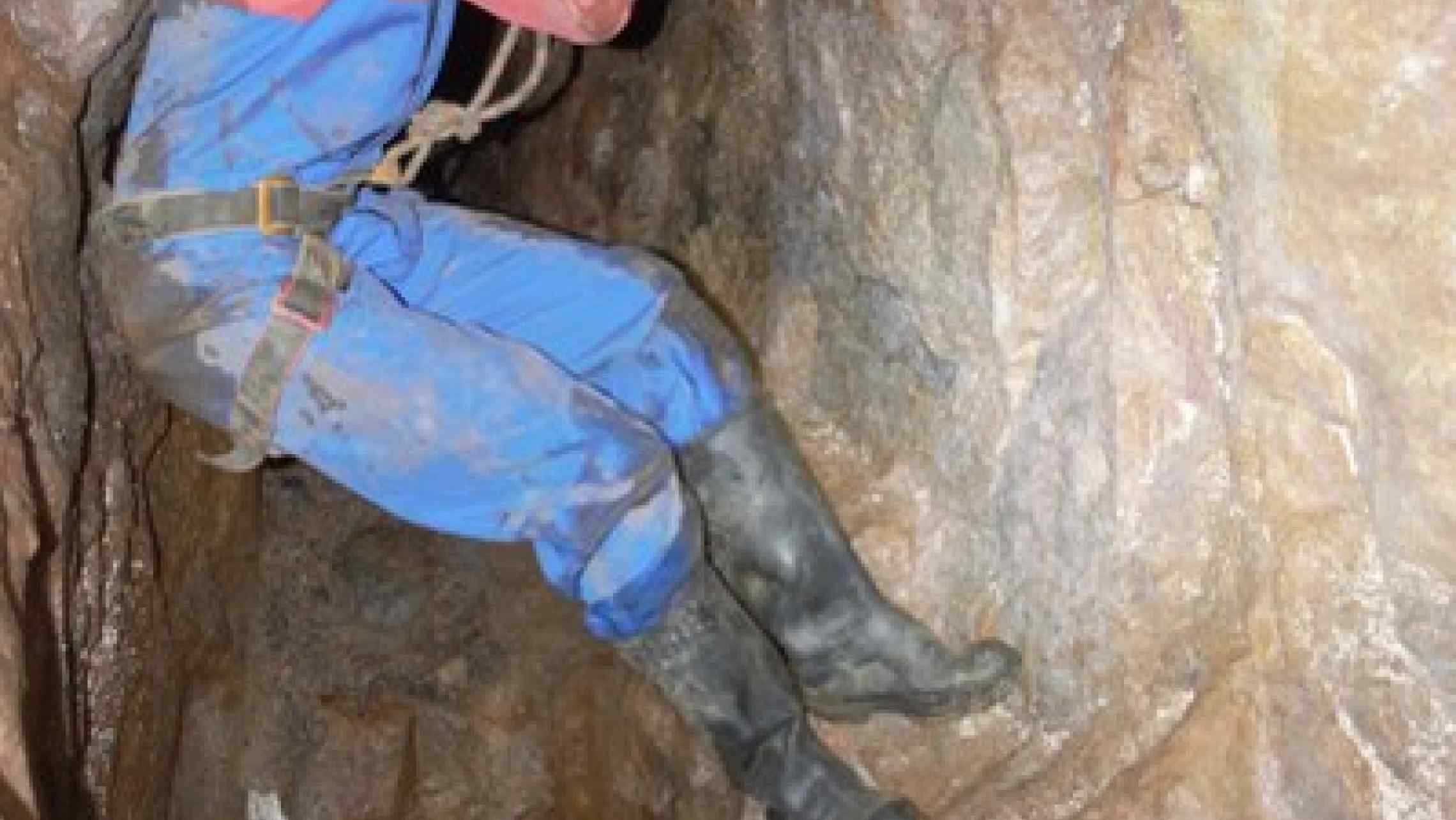 A mine explorer carefully negotiates a deep chasm in a Cornish tin mine with Cornwall Underground Adventures.